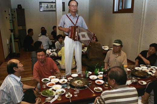 서화전을 찾은 지인들이 근처 식당에서 간단한 모임을 가진 자리에서 이계인 전 교통부장관이 즉석에서 아코디온 연주로 축하를 전했다. 왼쪽에 정희성, 신경림 시인이 보인다. 